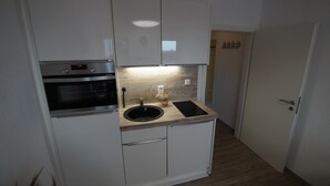 A compact kitchen with white cabinets, a built-in oven, a sink, and a wooden countertop. - Neue Ferienwohnung für 2 P. in Sehr Guter Lage! (Borkum)