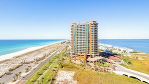 Hotel alto com várias varandas, situado perto de uma praia e com vista clara para o oceano.