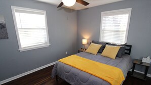 A bedroom with a bed, nightstands, a ceiling fan, and two windows with blinds. - Recently remodeled house near Expo, TU,  Rt 66, Downtown with large fenced yard (Tulsa)