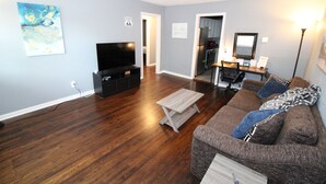 A living room with hardwood flooring, a TV, a sofa, and a coffee table. - Recently remodeled house near Expo, TU,  Rt 66, Downtown with large fenced yard (Tulsa)