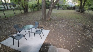 An outdoor seating area with a table and four chairs, surrounded by trees and a fenced yard. - Recently remodeled house near Expo, TU,  Rt 66, Downtown with large fenced yard (Tulsa)