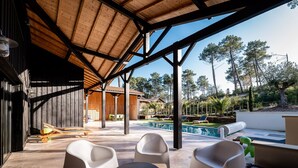 Un patio al aire libre con piscina, terraza de madera y sillas de descanso.