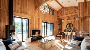 Amplia sala de estar con una televisión grande, paredes de madera y un comedor con barra.