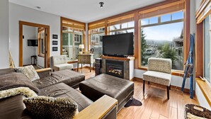 A modern living room with a large flat-screen TV, leather sofas, and a fireplace.