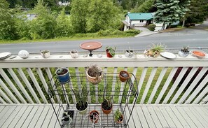 Enjoy the serene view from this balcony, surrounded by lush potted plants and a glimpse of the surrounding landscape.