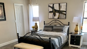 A bedroom with a bed, bedside tables, a bench, a ceiling fan, and a window. - Havasu Retreat with Pool and  Game Room-pet friendly. (Lake Havasu City)