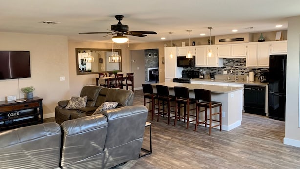A modern kitchen with white cabinets, a black refrigerator, and a central island with bar stools. - Havasu Retreat with Pool and  Game Room-pet friendly. (Lake Havasu City)
