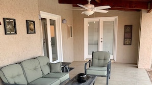 A covered patio area with a sectional sofa, a single chair, and a small table. - Havasu Retreat with Pool and  Game Room-pet friendly. (Lake Havasu City)