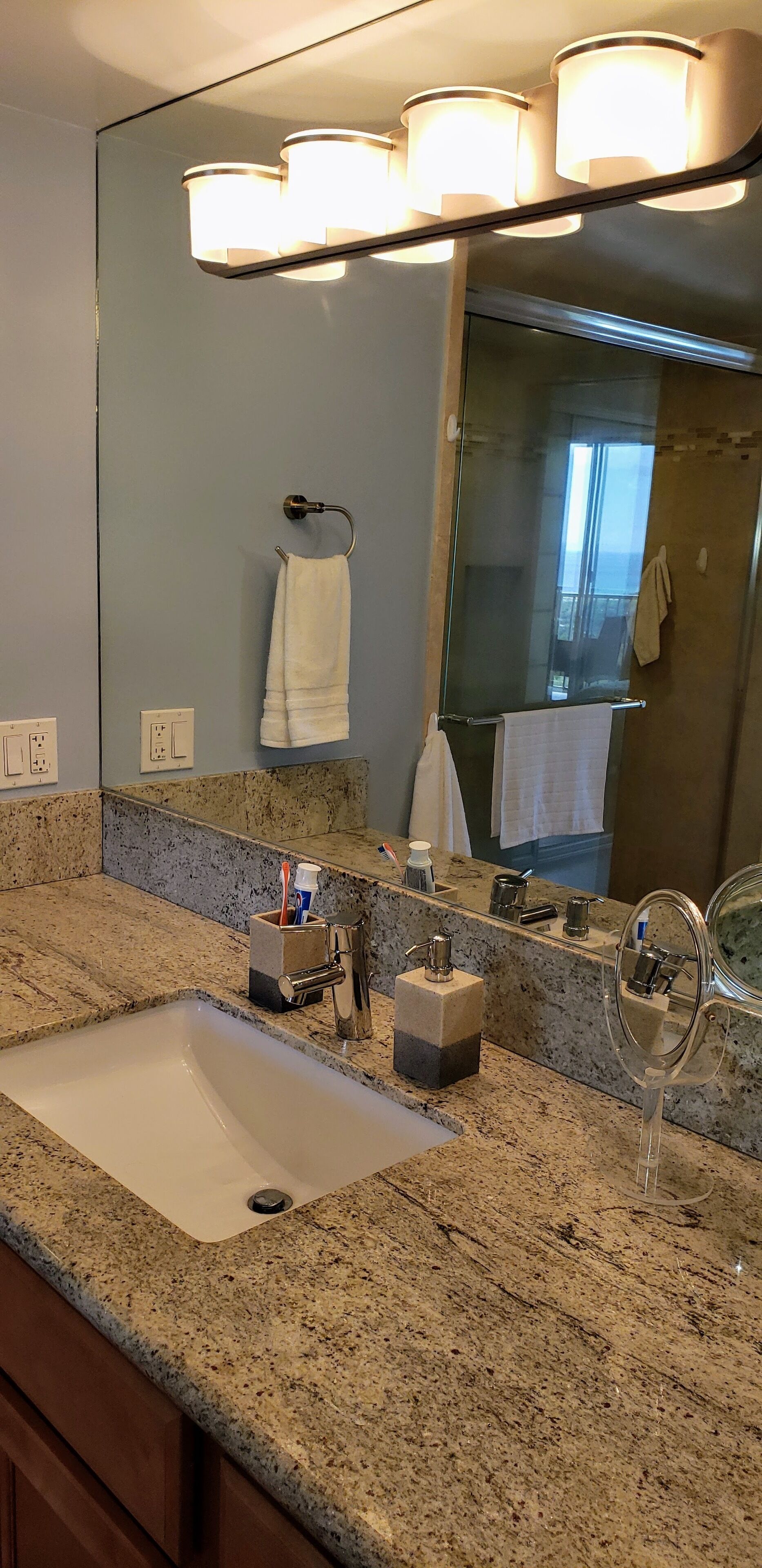 A bathroom with a granite countertop, a sink, a mirror, and a towel rack.