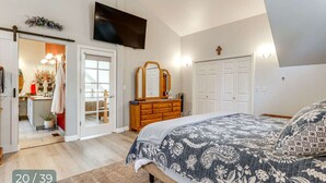 Un dormitorio con cama, cómoda, televisor y puerta que da a un baño.