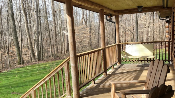 Eine Holzterrasse mit Adirondack-Stühlen, einer Brüstung und Blick auf ein bewaldetes Gebiet.