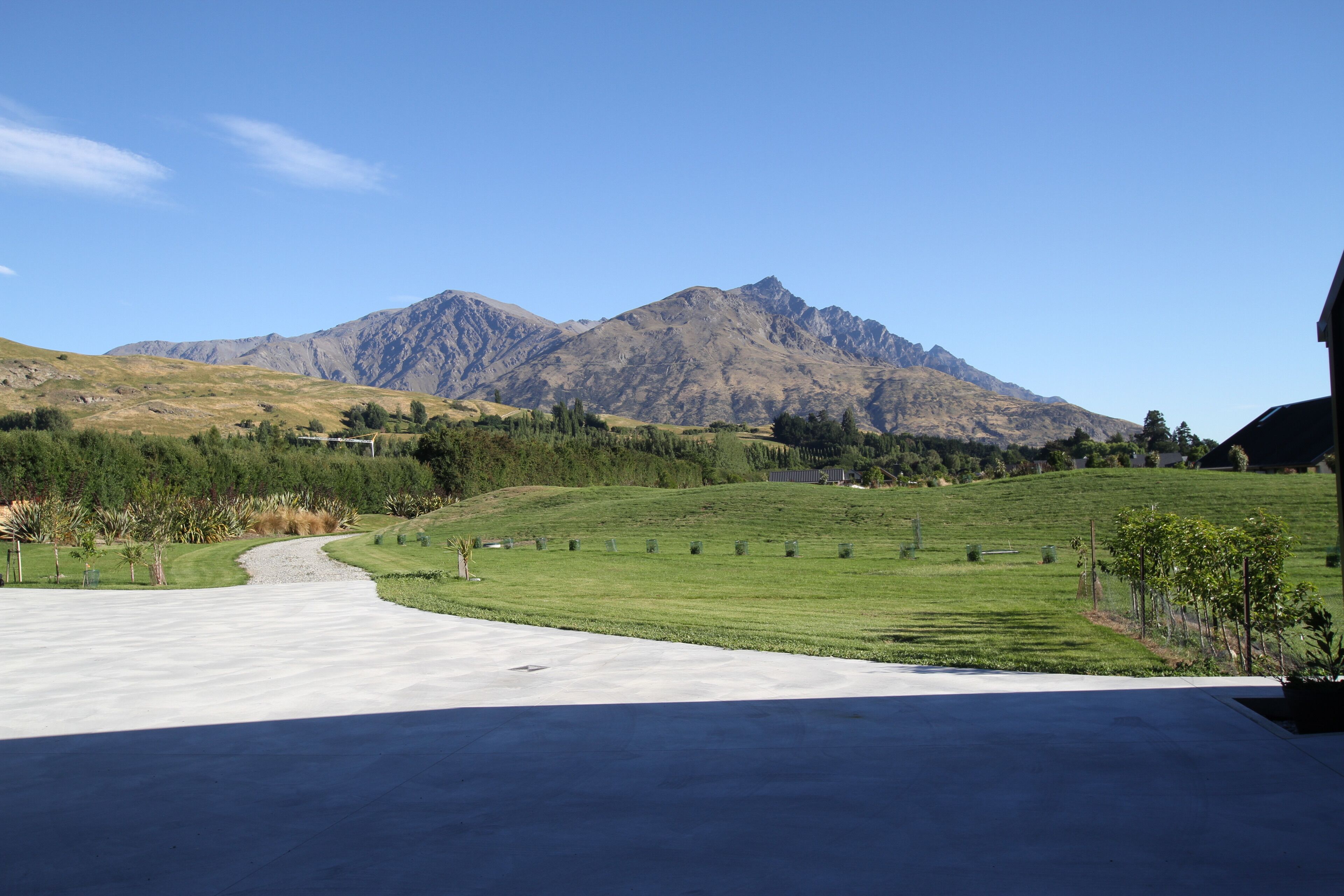 A residential driveway leading to a house with a mountain backdrop.
