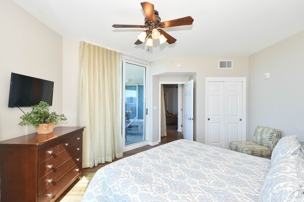 A bedroom with a bed, a dresser, a ceiling fan, a TV, and a sliding glass door leading to a balcony. - Updated 2 Bedroom Condo on the 6th Floor at The Palms of Destin 2616 (Destin)