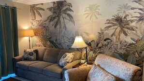 A living room with a sofa, two armchairs, a coffee table, and a lamp. The walls have a tropical mural. - Only 200 Steps to the Huge Oceanfront Pool (Hilton Head Island)