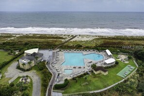 Vista aérea de una propiedad costera con piscina, cancha de tenis y acceso a la playa.