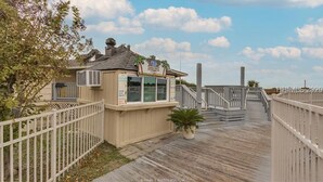 A wooden boardwalk leading to a small building with a sign, surrounded by a fence and palm trees. - Only 200 Steps to the Huge Oceanfront Pool (Hilton Head Island)