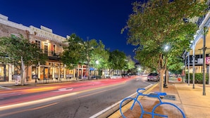 A street at night with a blue bicycle parked on the sidewalk.