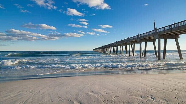A beach with a pier extending into the ocean.