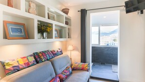 A modern living room with a grey sofa, colorful cushions, a small table, and a TV mounted on the wall. - LA TERRASSE DU PORT AP4212 (Niza)