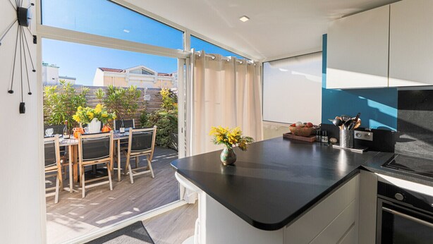 A modern kitchen with a large island, a dining area with a table and chairs, and a view of the city through large windows. - LA TERRASSE DU PORT AP4212 (Niza)