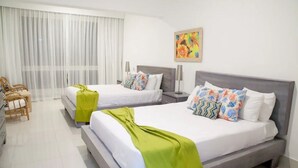 Une chambre d’hôtel avec deux lits, une chaise, un bureau et une grande fenêtre avec des rideaux légers.