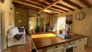 A cozy kitchen with a wooden ceiling, a white stove, and a dining area with a table and chairs.