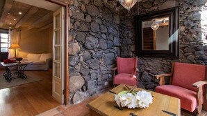 A room with stone walls, a wooden coffee table with a vase of flowers, a red chair, and a hanging light fixture.