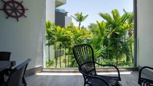Un balcon donnant sur un jardin tropical, une décoration en forme de roue de navire et un fauteuil moderne.