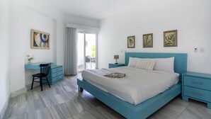 Une chambre moderne avec un grand lit, un bureau et une chaise. Trois tableaux encadrés ornent le mur.
