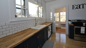 A modern kitchen with a wooden countertop, white subway tiles, a gold faucet, and a stainless steel oven. - Vintage Gem in the Heart of Sheridan (Sheridan)