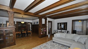 A spacious living room with a wooden ceiling, a sofa, a patterned rug, and a dining area with chairs and a table. - Vintage Gem in the Heart of Sheridan (Sheridan)