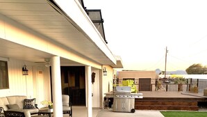 Una zona patio coperta con pavimento in cemento, arredi da esterno e un barbecue.