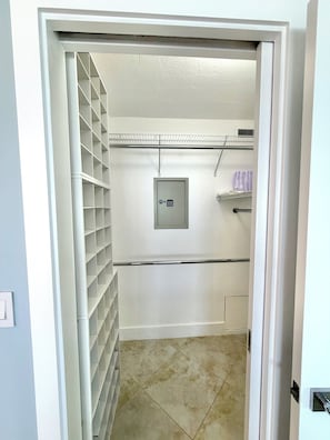 A storage closet with shelves, a utility box, and a tiled floor.