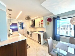 A modern kitchen with a built-in oven, a sink, and a dining area with a table and chairs.