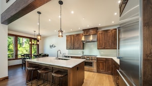 A modern kitchen with wooden cabinets, stainless steel appliances, and a large island with bar stools. - Beautiful Suncadia House With Two Master Bedrooms and plenty of space for kids!  (Cle Elum)