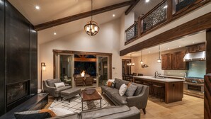 A spacious living area with a fireplace, leather sofas, and a dining area with a kitchen in the background. - Beautiful Suncadia House With Two Master Bedrooms and plenty of space for kids!  (Cle Elum)