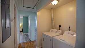A laundry room with two white washers and dryers, a vent hose, and a light fixture on the ceiling. - Fins Up Unit #2 - On The Bayside - Downtown - Spacious Unit! (Ocean City)