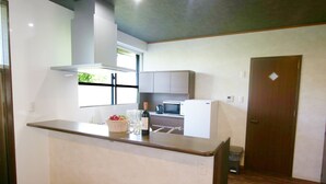 A compact kitchen with a countertop, a microwave, a refrigerator, and a window. - Pool Villa Sesoko jima (Motobu)
