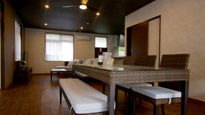 A spacious room with a dining table, two wicker chairs, a bench, and a sofa. - Pool Villa Sesoko jima (Motobu)