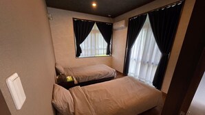 A small, compact room with two single beds, a small table, and a window with curtains. - Pool Villa Sesoko jima (Motobu)