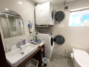 Bathroom features a sink, mirror, toiletries shelf, toilet, washing machine, and a window.