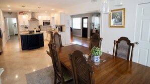 A spacious dining area with a wooden table and chairs, a kitchen in the background, and a framed picture on the wall. - Beautiful waterfront pool home 5 minutes from downtown St Pete! (St. Petersburg)