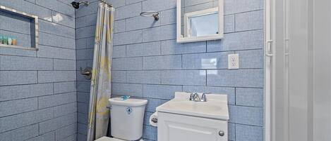 A bathroom with a toilet, sink, and shower area.
