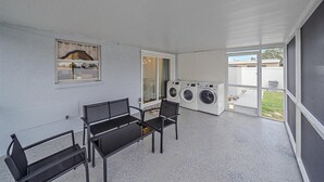 Et vaskerum med to vaskemaskiner, en bænk og et vindue med udsigt ud