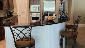 A modern kitchen with a central island, built-in appliances, and bar stools. - Entire private house VR24-00064  (Sarasota)