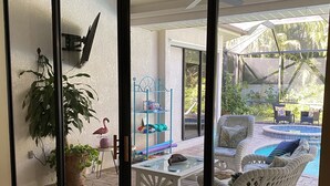 A patio area with a white wicker sofa, a glass table, and a ceiling fan. - Entire private house VR24-00064  (Sarasota)