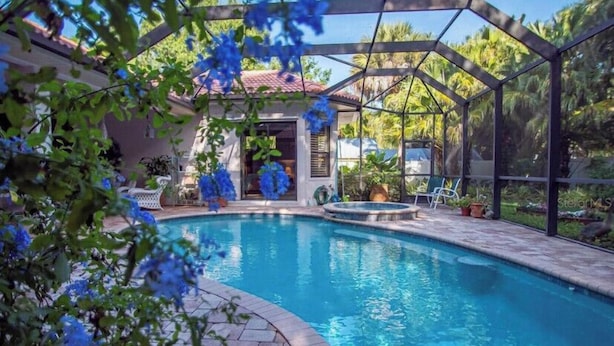 A swimming pool with a covered area, surrounded by greenery and potted plants. - Entire private house VR24-00064  (Sarasota)