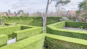 En vackert anlagd trädgård med geometriskt utformade labyrinter av häckar och ett högt träd.
