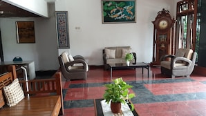 Un hall d’entrée spacieux, avec un canapé, des fauteuils, une table basse et une plante en pot.