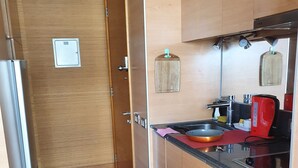 Una cocina con armarios de madera, un refrigerador de acero inoxidable, un hervidor rojo y un horno empotrado.